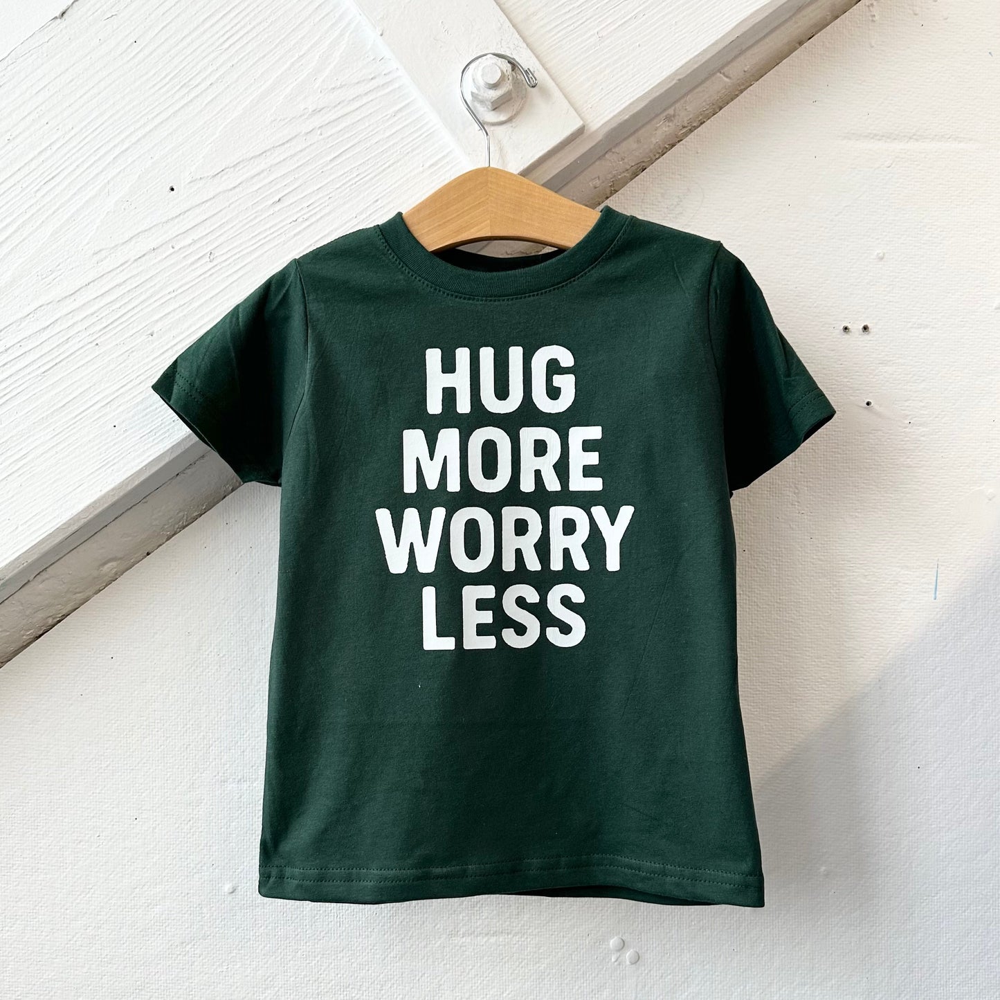 Green "Hug More Worry Less" plush pillow by The Wishing Elephant featuring soft fabric and motivational message.