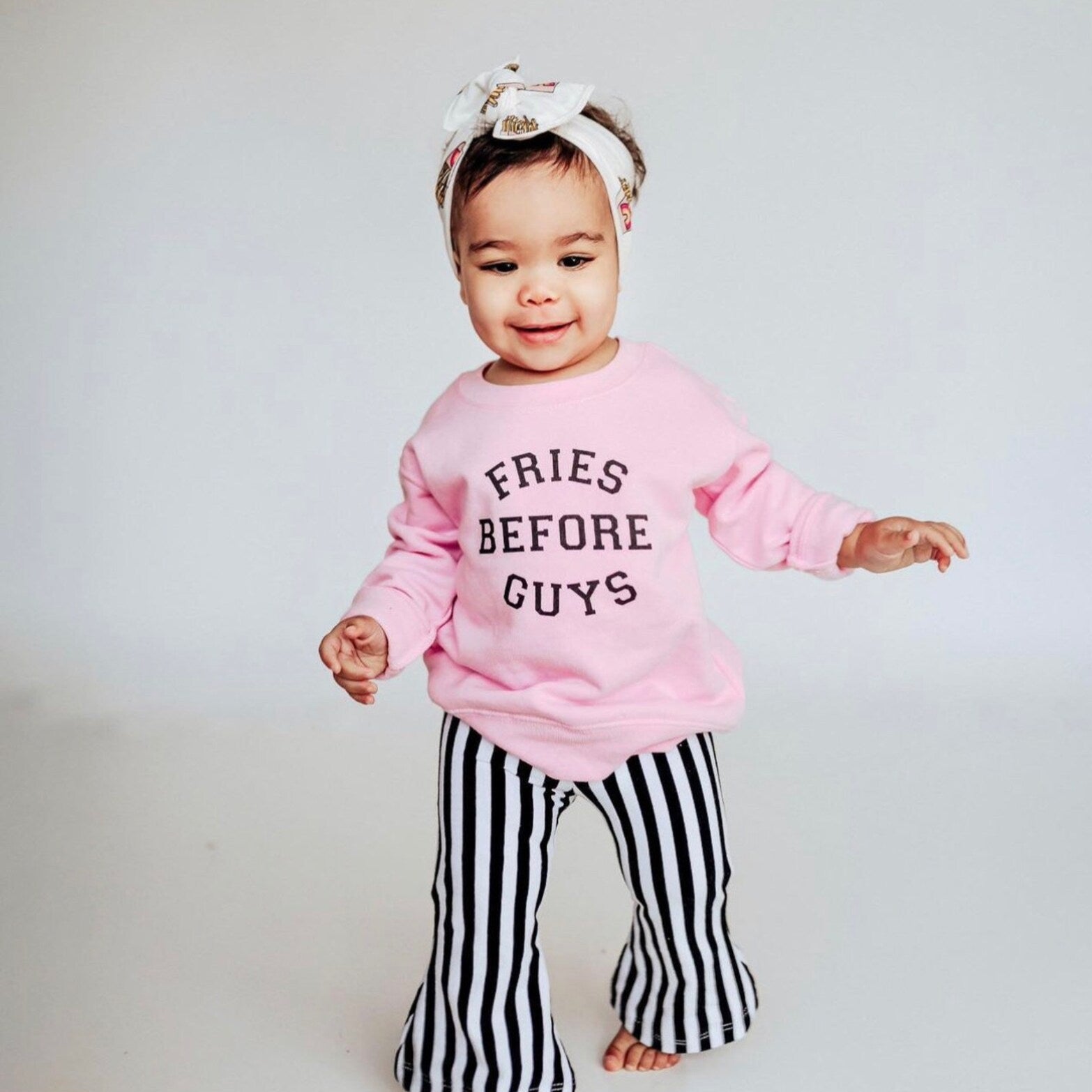 Toddler girl wearing Fries Before Guys sweatshirt and striped pants