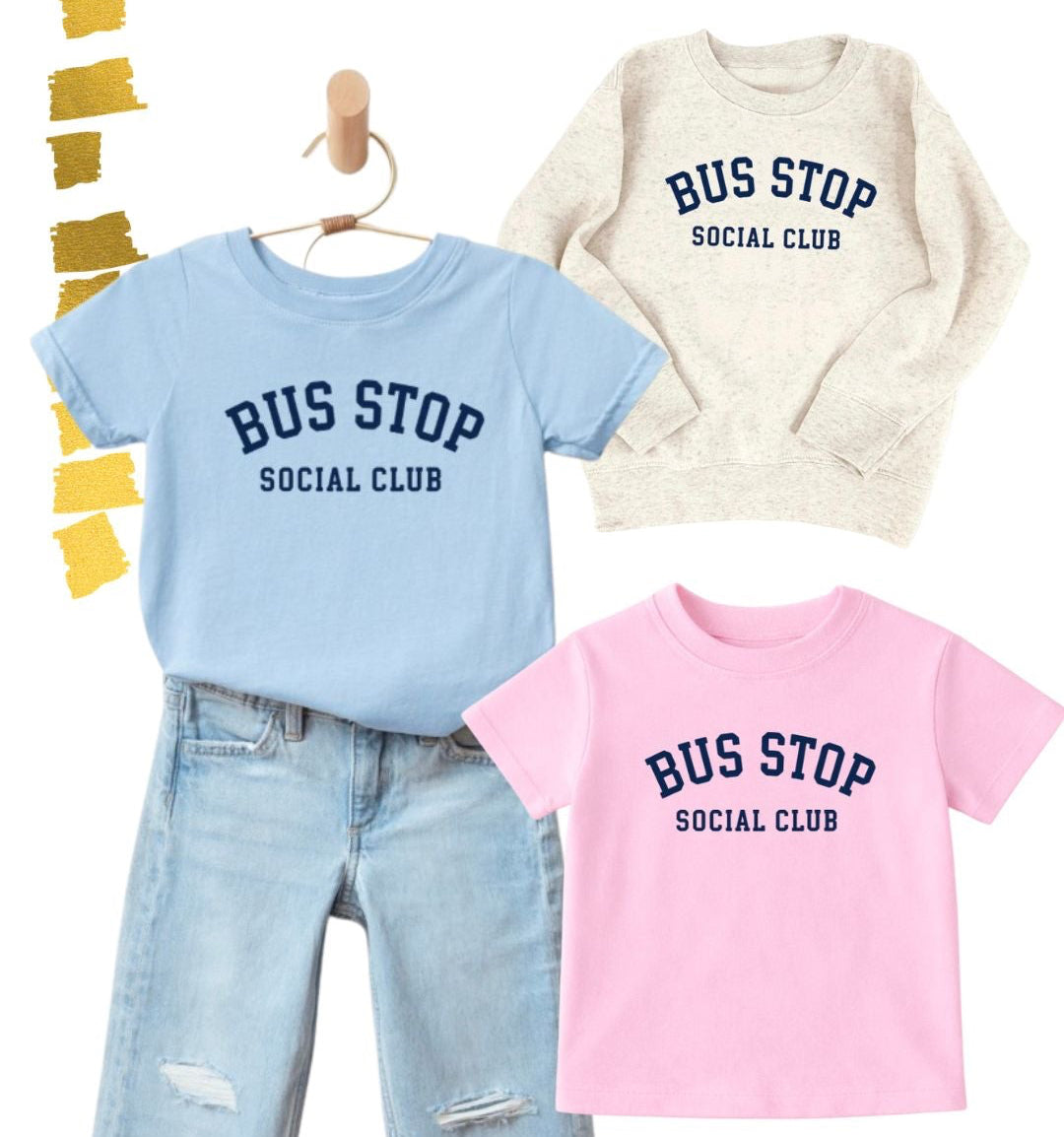 Three children's outfits displayed on a white background: a light blue short-sleeve T-shirt with distressed light-wash jeans, a cream sweatshirt, and a pink short-sleeve T-shirt. Each top has the text 'BUS STOP SOCIAL CLUB' printed in dark blue.