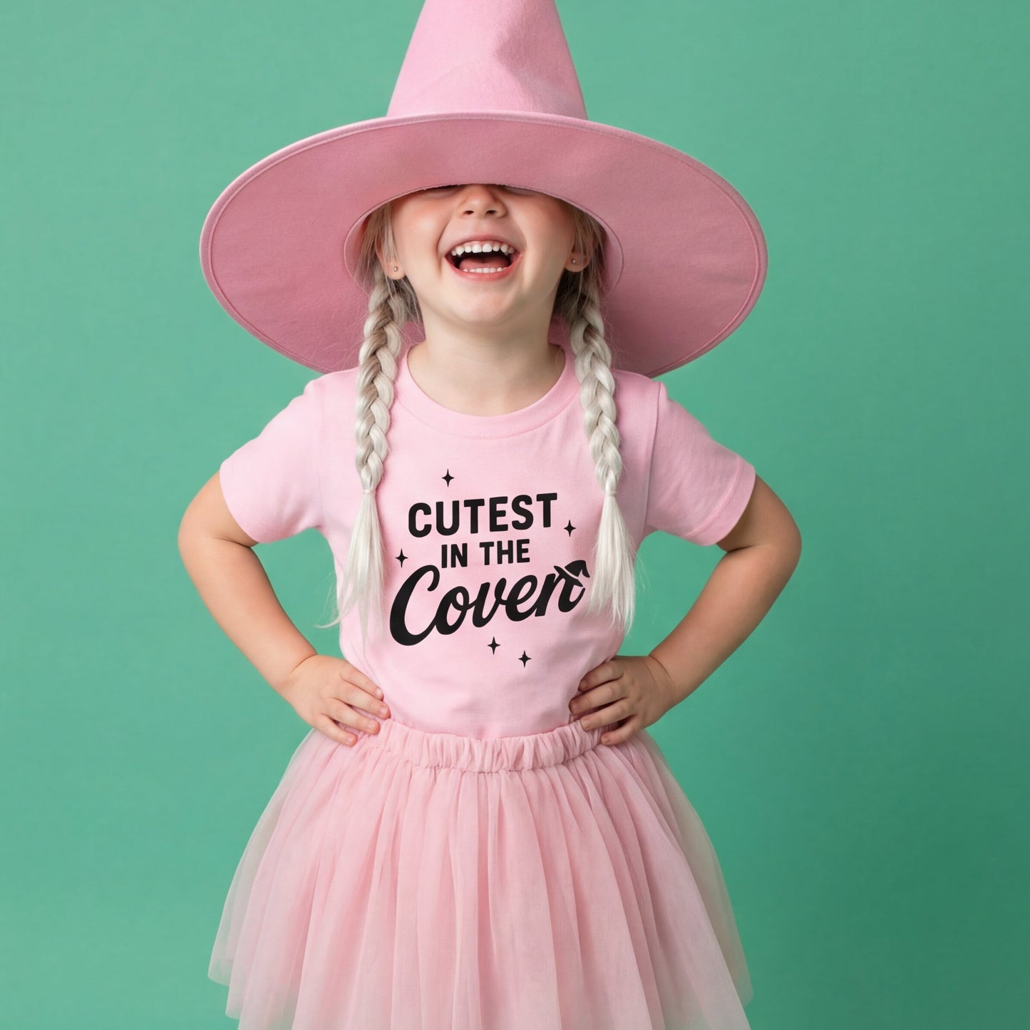Child wearing a pink witch costume with a hat, dress, and shoes on a green background