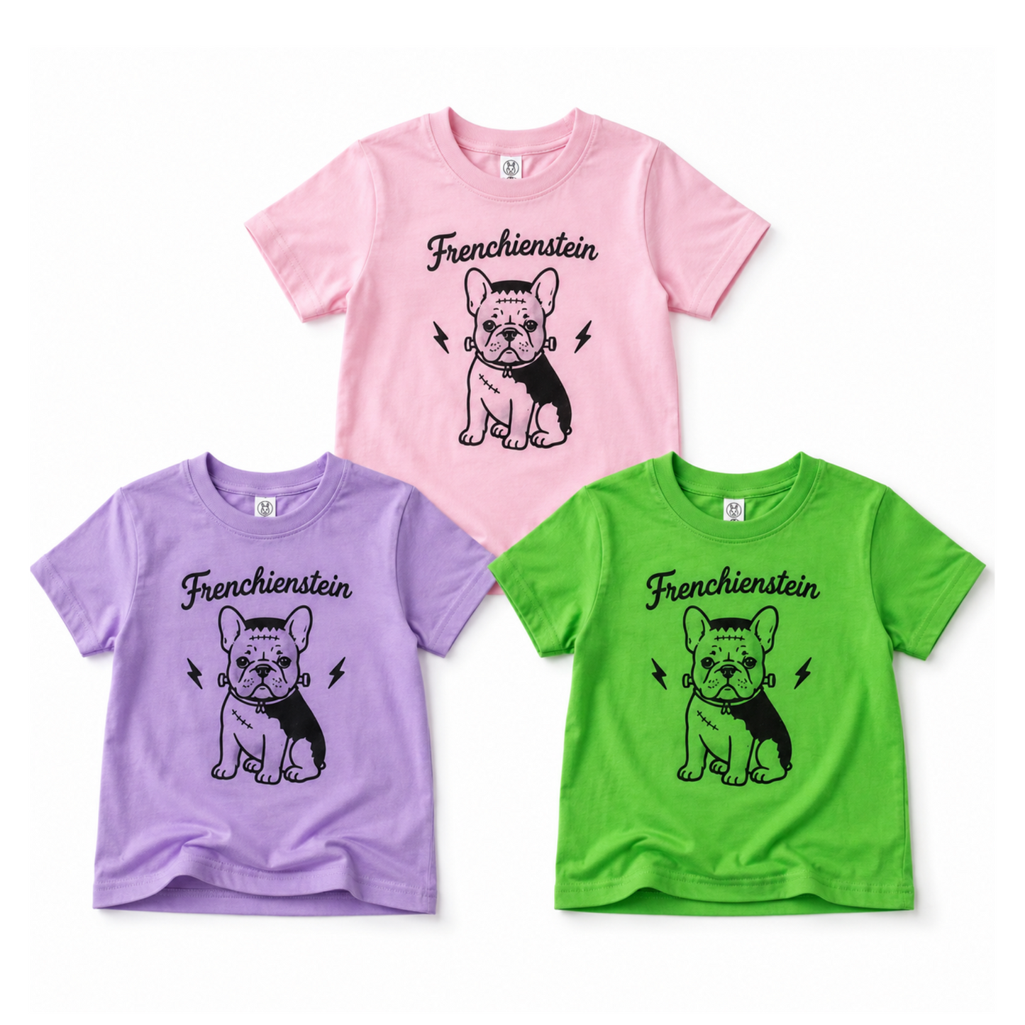 Three short-sleeve children's T-shirts in pink, purple, and green, each printed with a black-and-white French Bulldog graphic and the word 'Frenchstein' on the chest, displayed on a plain white background.