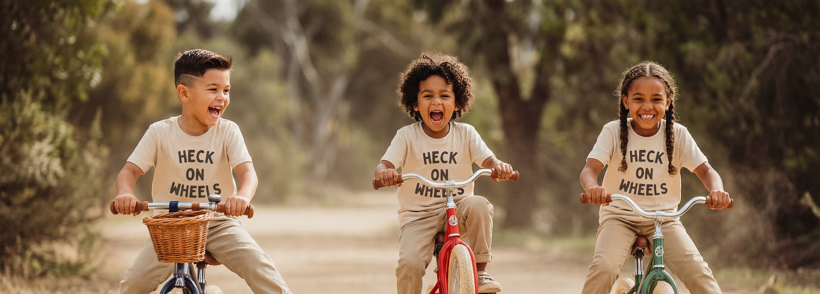 Three children riding bicycles on a dirt road with 'HECK ON WHEELS' graphic t-shirts.