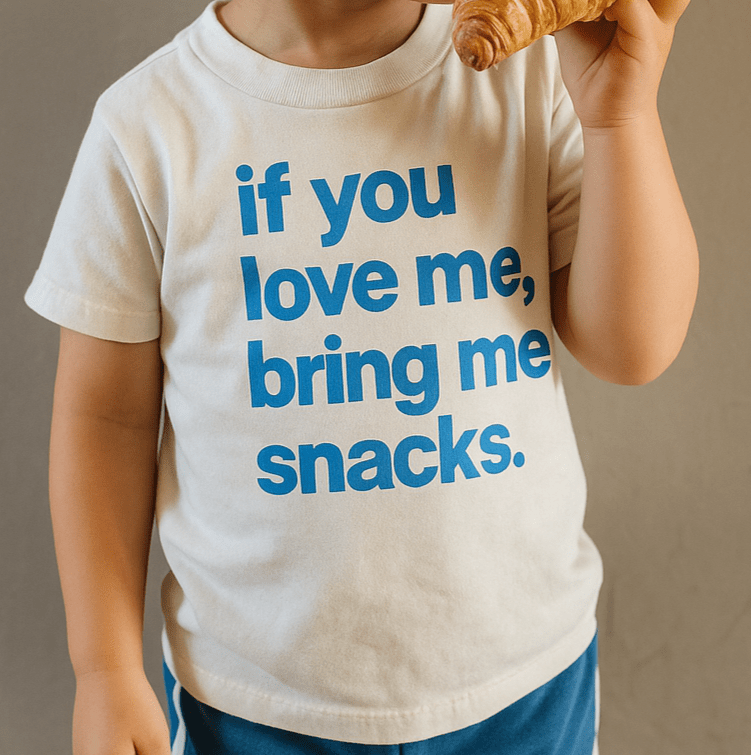 Graphic T-shirt by The Wishing Elephant featuring "If you love me, bring me snacks" text, worn by kids and adults.