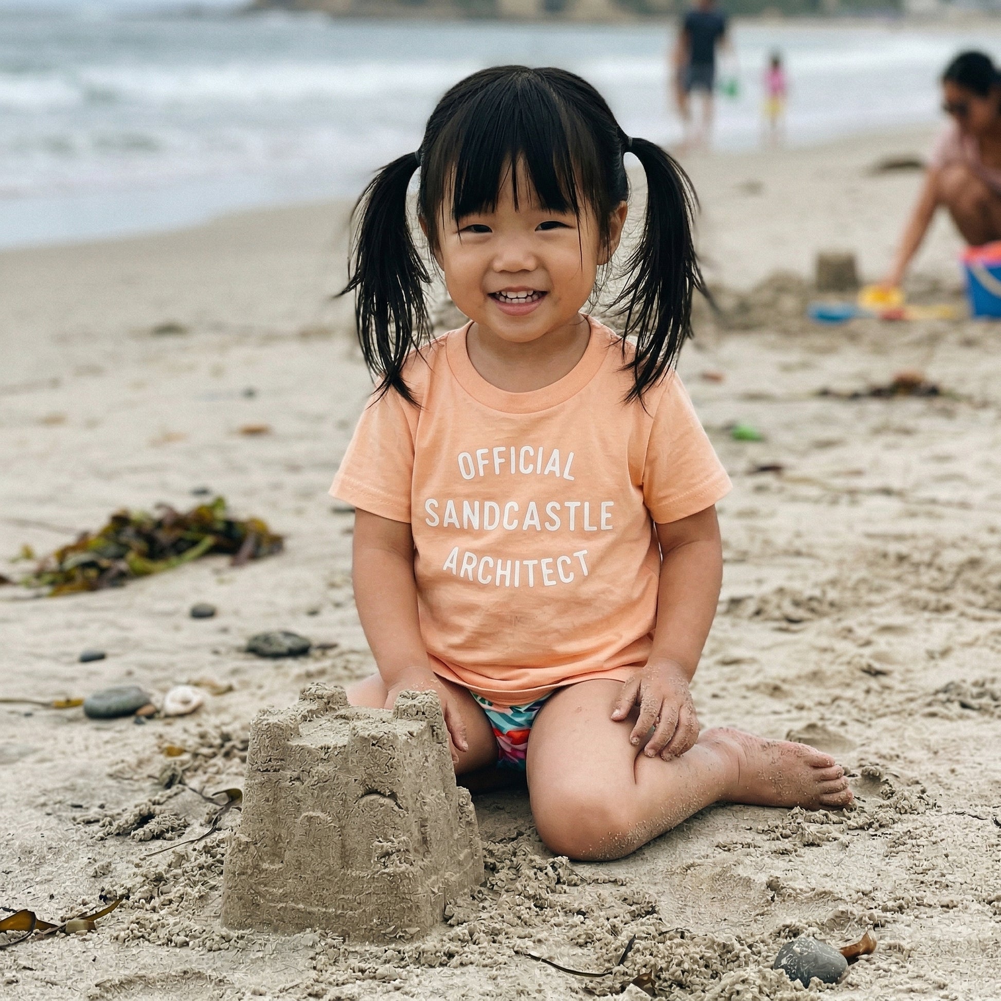 Kids graphic T-shirt featuring a fun sandcastle architect design, perfect for summer beach days, by The Wishing Elephant.