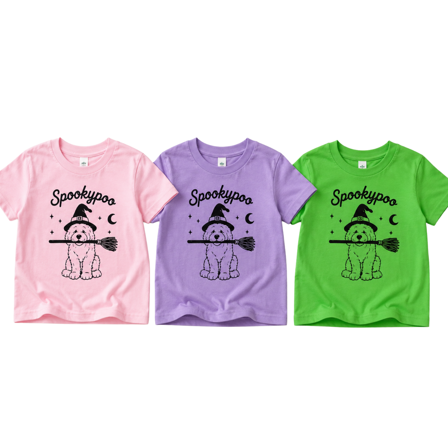 Three children's short-sleeve T-shirts shown side by side on a plain white background: pink, lavender, and bright green. Each shirt has a black 'Spookypoo' graphic with a dog illustration, witch hat, broom, crescent moon, and stars.