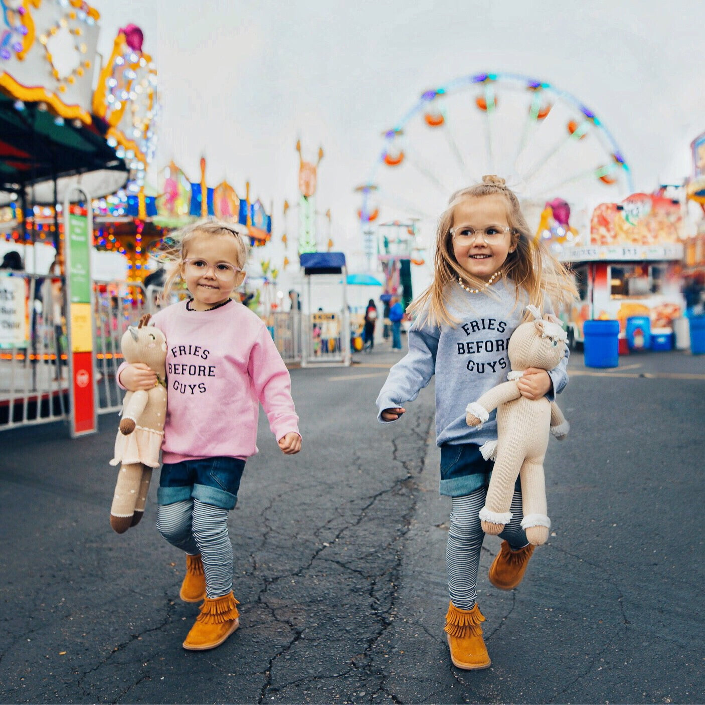two girls at a carnival holding stuffed animal in fries before guys sweatshirts